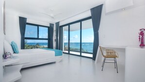 A modern bedroom with a bed, a chair, and a view of the ocean. - Beachfront without seaweed, infinity pool, rooftop jacuzzi, Chef included. (TULUM)