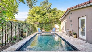 A rectangular swimming pool with a tiled deck, surrounded by a wooden fence and lush greenery. - Heated pool, parking, 5 min walk to food and fun! (Wilton Manors)