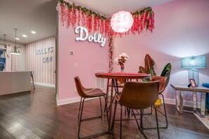 Cozy space with a round dining table and comfortable seating for four, featuring a decorative plant arrangement and a large potted plant.