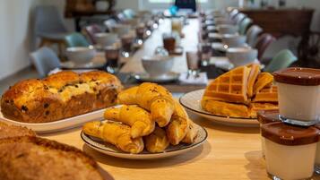 Ein Frühstücksbuffet mit Croissants, Waffeln und einer Auswahl an Gebäck.