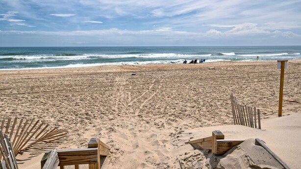 A sandy beach with wooden structures, a clear sky, and the ocean in the background. - Oceanfront 2BR/2 Bath Second Floor Condo with Pool and Oceanfront Deck (Rodanthe)