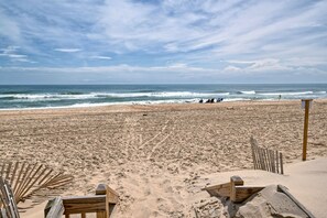 A sandy beach with wooden structures, a clear sky, and the ocean in the background. - Oceanfront 2BR/2 Bath Second Floor Condo with Pool and Oceanfront Deck (Rodanthe)