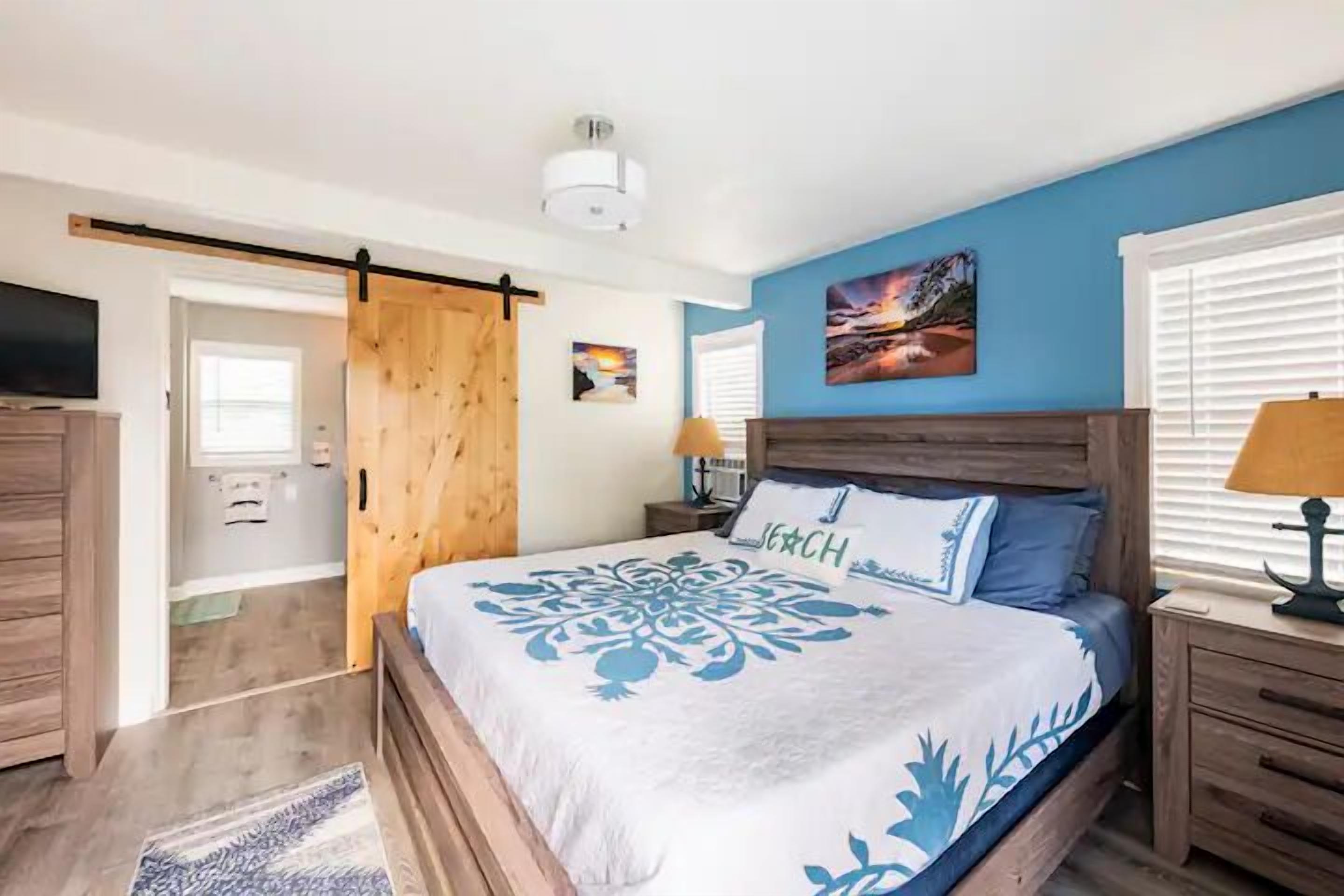 Un dormitorio con cama, cabecera de madera, mesitas de noche y televisor.