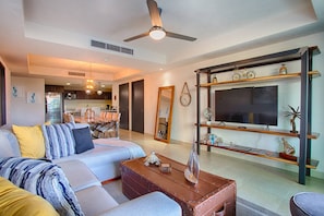 A modern living room with a sofa, coffee table, and a TV on a wooden shelf.