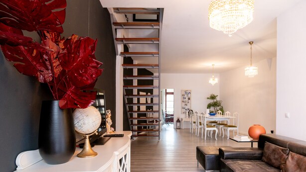 A modern living room with a staircase, a dining area, and a chandelier.