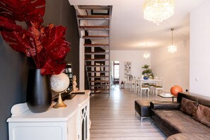 Una sala de estar moderna con una escalera, un comedor y una araña.