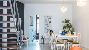A dining area with a white table, chairs, and a chandelier.