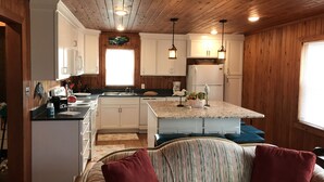 Una cocina acogedora de estilo rústico, con paredes de madera, una isla central e iluminación colgante.