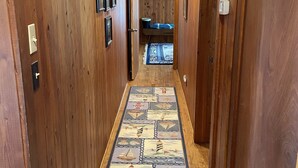 Un pasillo de madera con alfombra estampada, paredes de madera y una puerta a la derecha.