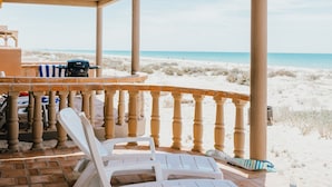 A beachside patio with a view of the ocean, featuring a covered seating area with chairs and a grill. - The Suites at Rocky Point 2 (Puerto Peñasco)