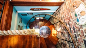 Uma escada em espiral com decoração em corda, parede de madeira e uma placa com a inscrição 'Beach House'.