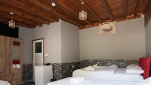 Un dormitorio con una cama grande, un armario de madera, un refrigerador blanco pequeño y una pared de acento de piedra.