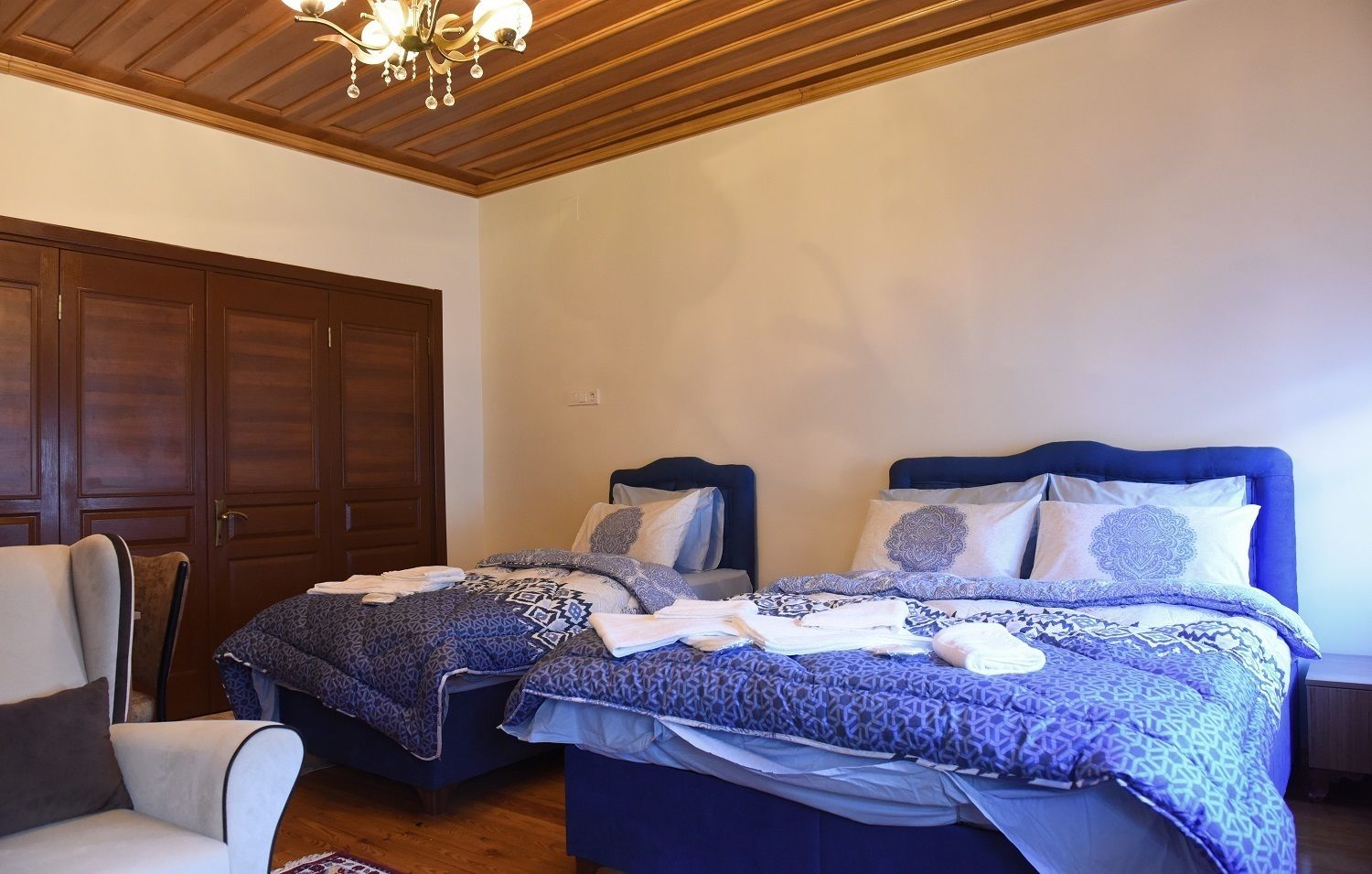 Un dormitorio con dos camas, un armario de madera y un candelabro.