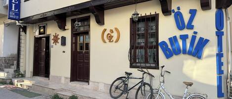 A building with a sign reading "ÖZ BUTIK HOTEL" and another sign for "ÖTEL". There are two bicycles parked outside.