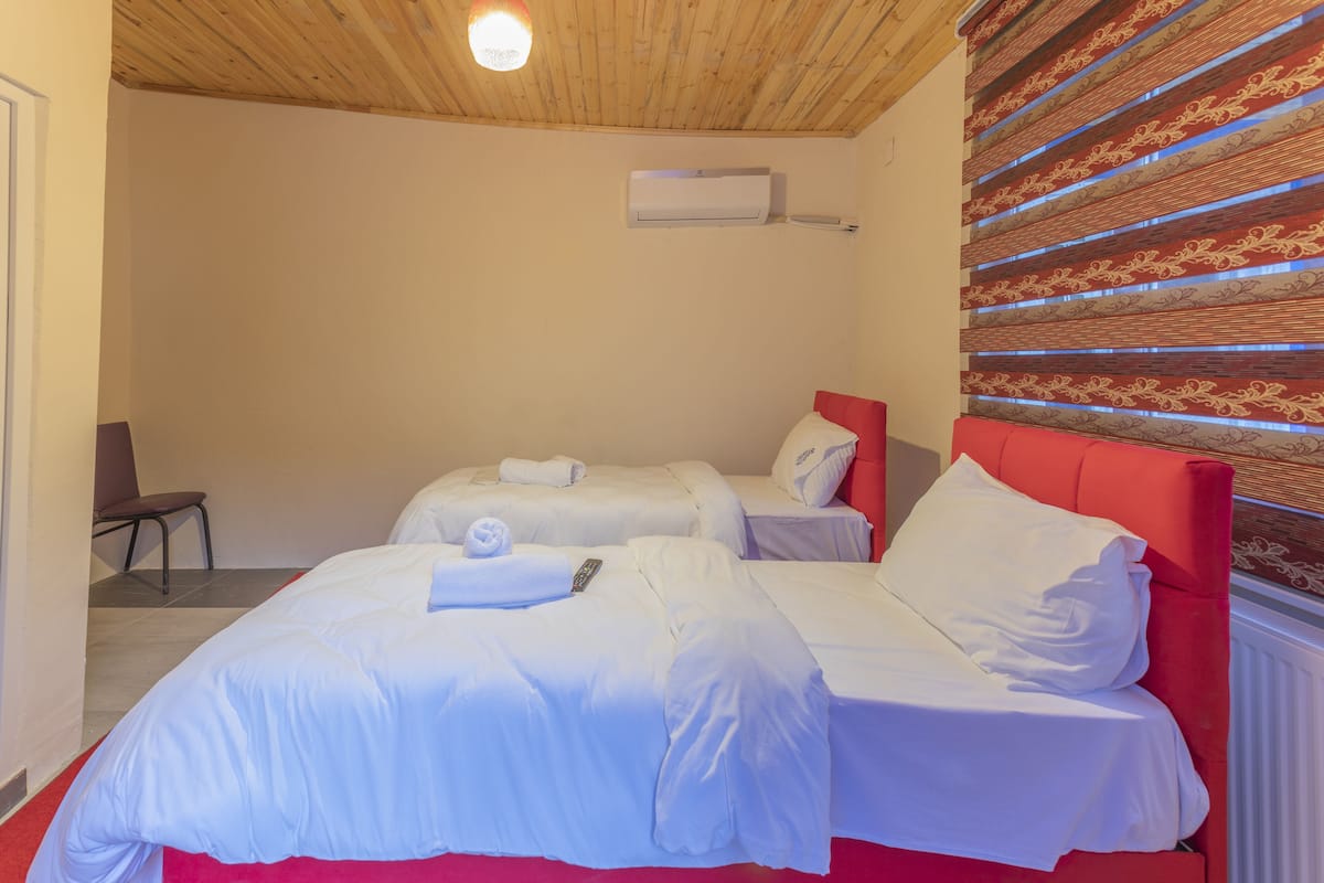 Habitación de hotel con dos camas, cabecera roja y pared con estampado.