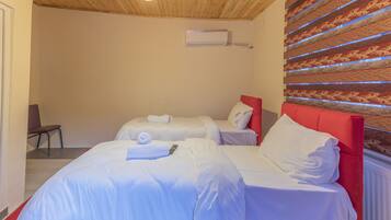 Habitación de hotel con dos camas, cabecera roja y pared con estampado.