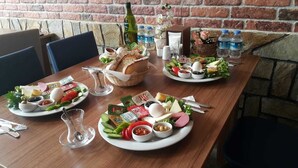 Una mesa servida para una comida con distintos platos, salsas y una botella de agua.