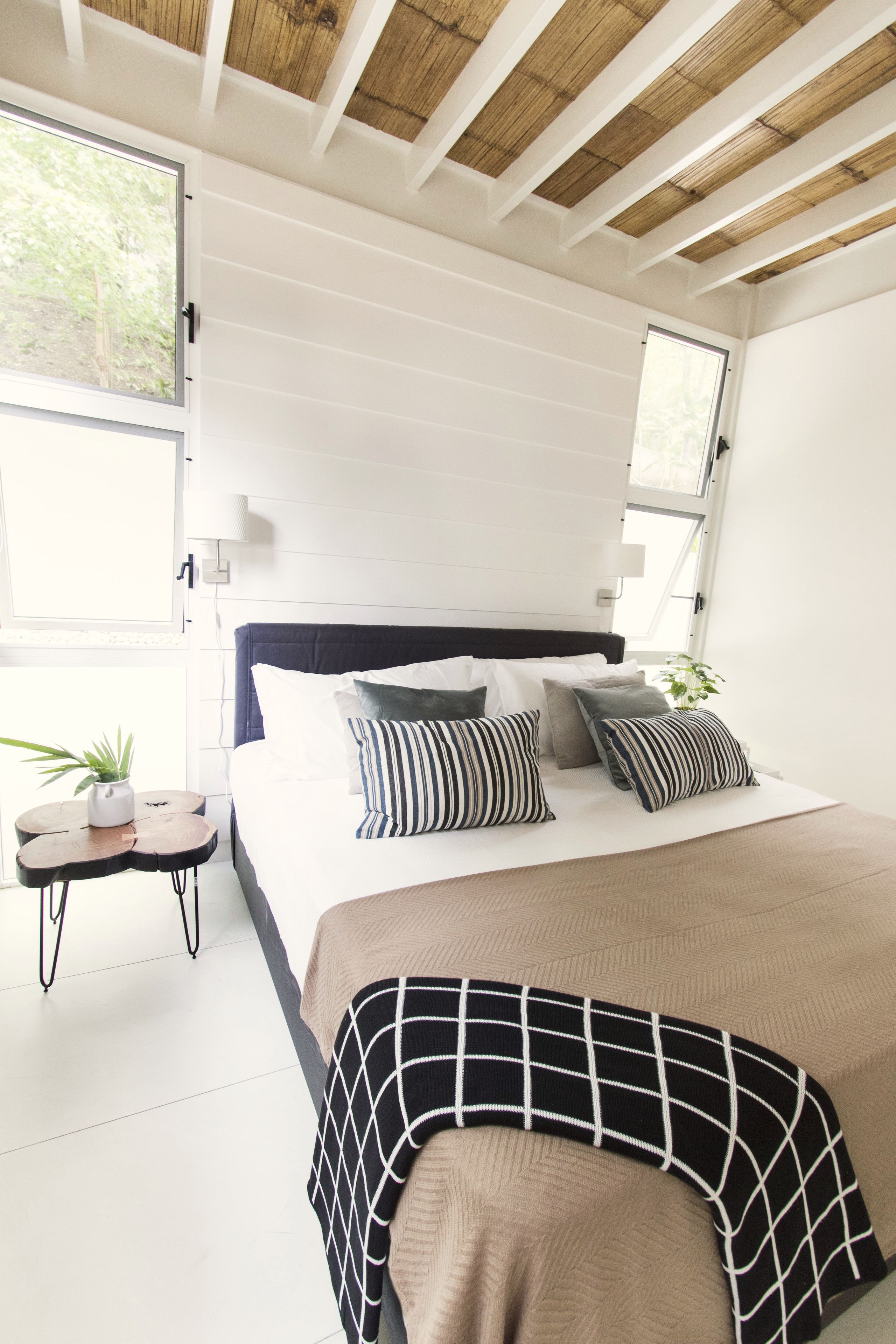 A bedroom with a bed, bedside tables, and a window.