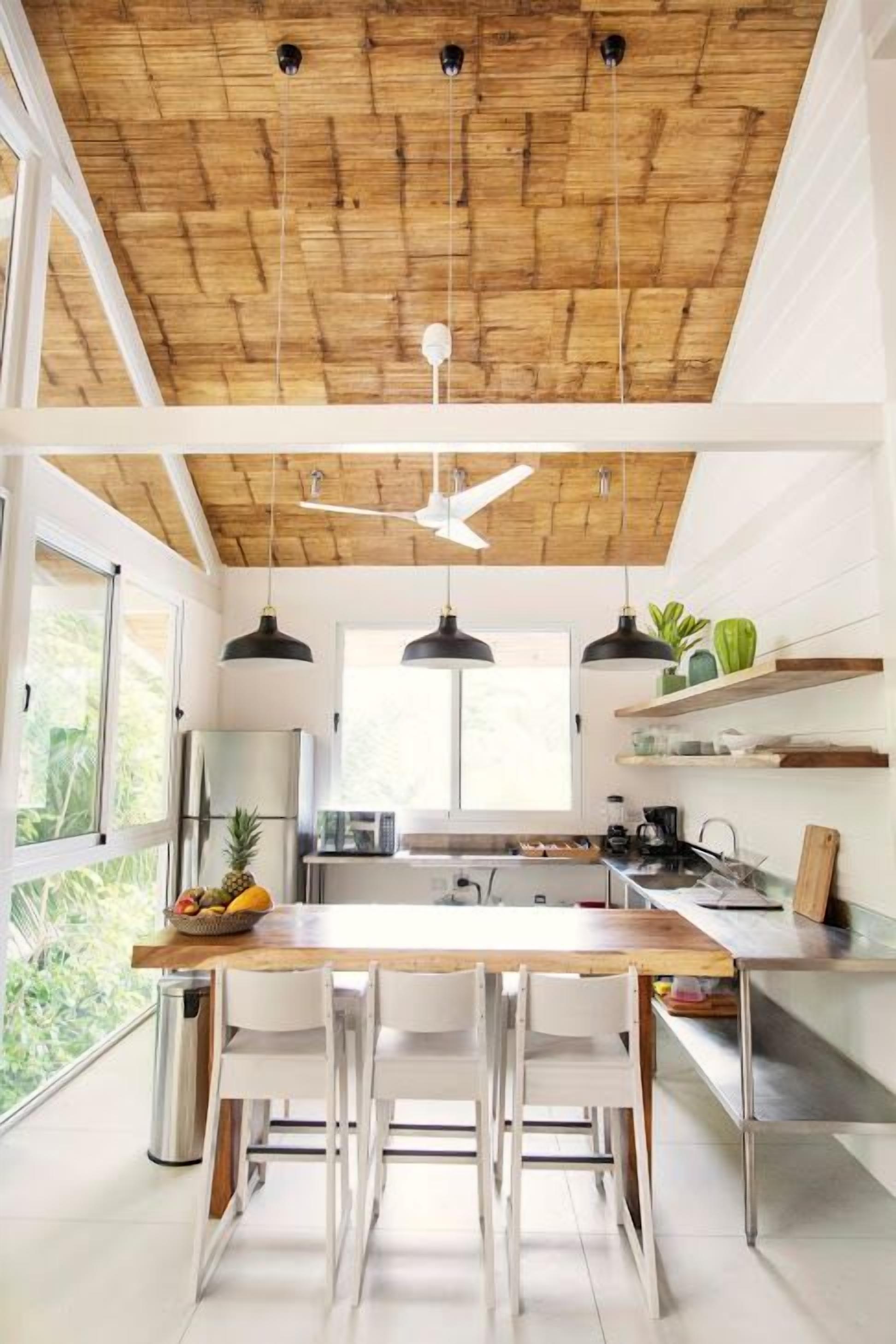 Une cuisine moderne avec un plafond en bois, des luminaires suspendus et un îlot central.