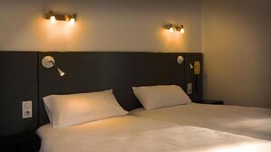 A hotel room with two beds, each with white linens, and wall-mounted lighting fixtures. - Hôtel Bonnet (Saint-Pee-sur-Nivelle)