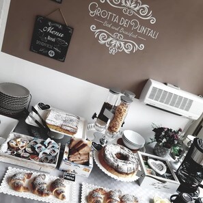 A breakfast buffet with various pastries, sandwiches, and a cake.