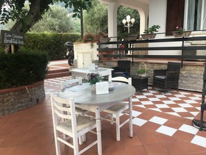 An outdoor dining area with a checkered floor, white chairs, and a table set for two.