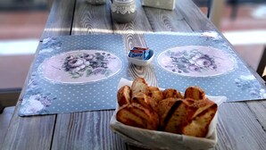 A wooden table with a floral tablecloth, a small vase with flowers, a decorative box, and a basket of bread. - Grotta dei Puntali (Carini)