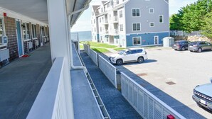 A hotel with a covered walkway, a parking area, and a building with multiple floors and balconies. - Completely updated 1 bedroom condo unit-steps to a shared private beach! (Dennis Port)