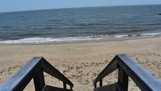 A beach with a wooden walkway leading to the water. - Completely updated 1 bedroom condo unit-steps to a shared private beach! (Dennis Port)