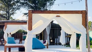 A wooden bed with a canopy, surrounded by white fabric, set on a sandy surface. - MOB 205 by Riviera Rentals (Playa del Carmen)