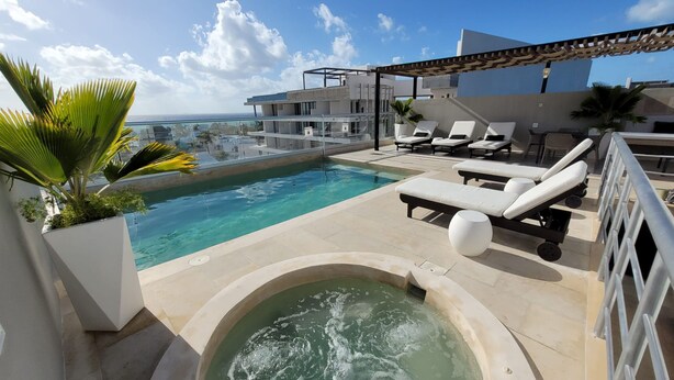 A rooftop pool with lounge chairs, a hot tub, and a view of the ocean. - MOB 205 by Riviera Rentals (Playa del Carmen)