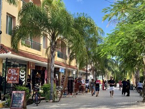 A street lined with palm trees and buildings, with shops and a signboard advertising a wine bar. - MOB 205 by Riviera Rentals (Playa del Carmen)