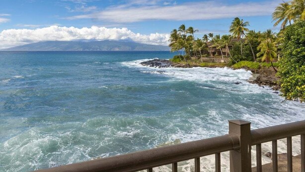 A coastal view with waves crashing onto a rocky shore, palm trees, and a clear sky. - Gorgeous Ocean Views Family Vacation Condo - Kahana Sunset C1 (Lahaina)