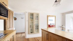 A modern kitchen with wooden cabinets, a built-in microwave, and a glass-fronted cabinet.