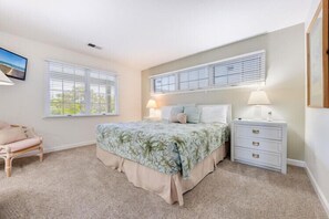 A bedroom with a bed, bedside tables, a chair, and a window.