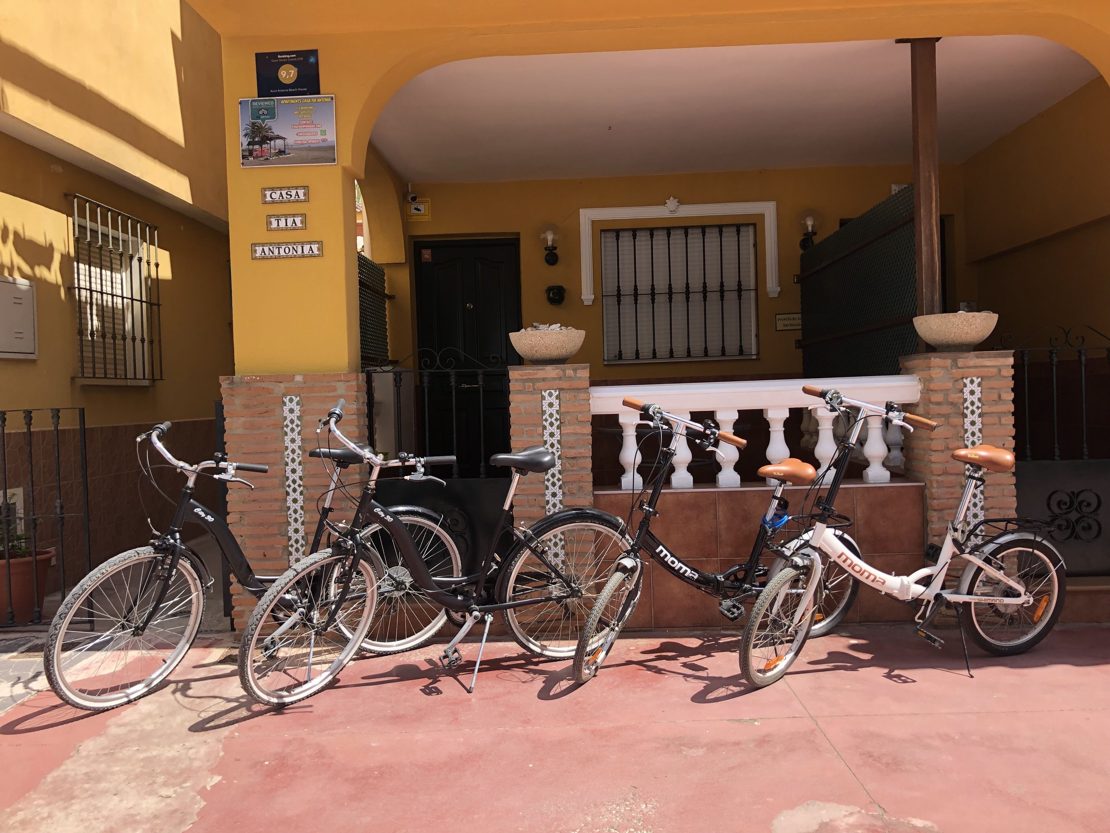 Un edificio con fachada amarilla, una reja negra y un cartel con nombres.