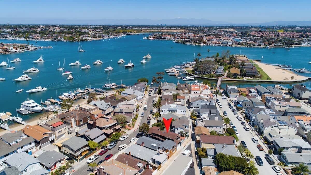 Eine Luftaufnahme einer Küstenstadt mit einem Hafen voller Boote, Wohnhäusern und einem Strand.