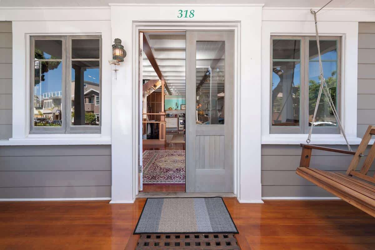 A house entrance with a number '318' above the door, a porch with a swing, and a visible interior with a staircase and a rug.