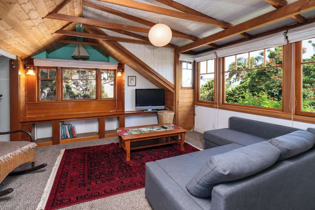 Ett mysigt vardagsrum med ett träpanelat tak, en tv, en soffa och ett stort fönster med utsikt över grönområden.