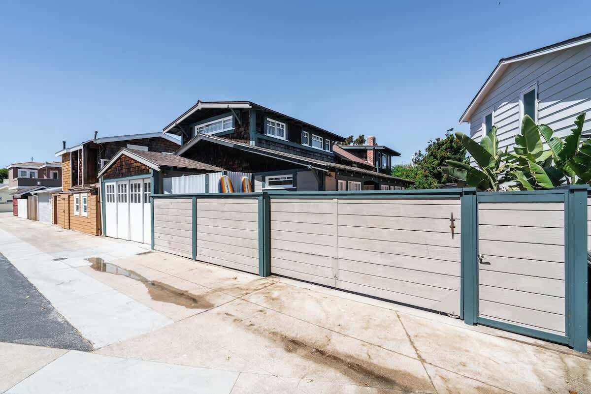 Une rue résidentielle bordée de maisons, avec une allée privée fermée par un portail et un ciel dégagé.