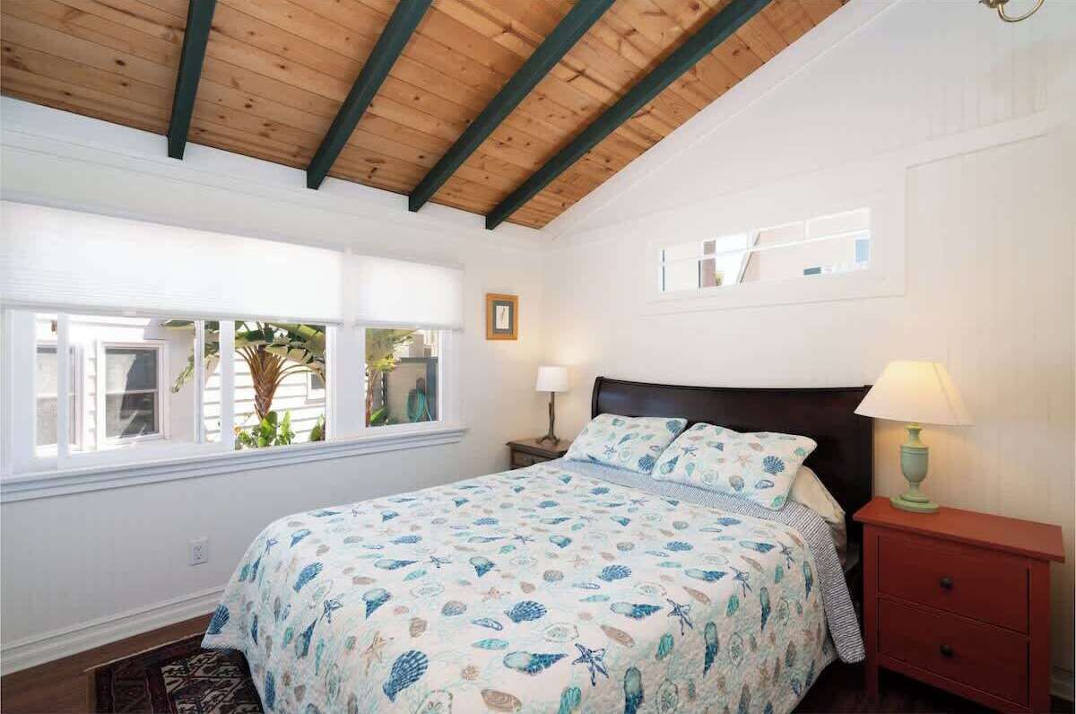 A bedroom with a bed, a nightstand, a lamp, and a window with blinds.