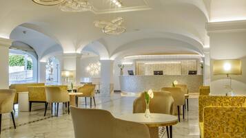 A hotel lobby with arched ceilings, chandeliers, and a reception desk.