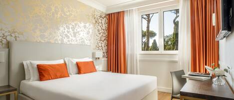 Habitación de hotel con una cama grande, un escritorio, una silla, un televisor y una ventana con cortinas.