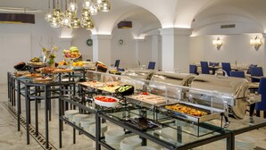 Montaje de bufé con diversas opciones de comida, vitrinas de vidrio y disposición de mesas.