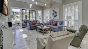 A spacious living room with a large TV, two sofas, a coffee table, and a dining area with outdoor views. - 29 Stoney Creek - Harbour Town is just a quick walk away - Dog Friendly (Hilton Head Island)