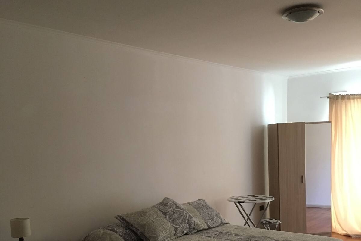 Escritorio, cortinas blackout y tabla de planchar con plancha