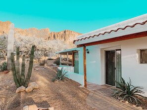 A desert-style house with a patio, cacti, and a view of rocky mountains.