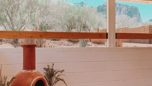 A patio area with a terracotta oven, potted plants, and a view of a desert landscape. - Casita at base of the Superstition Mountains. Unbelievable hiking and views. (Apache Junction)