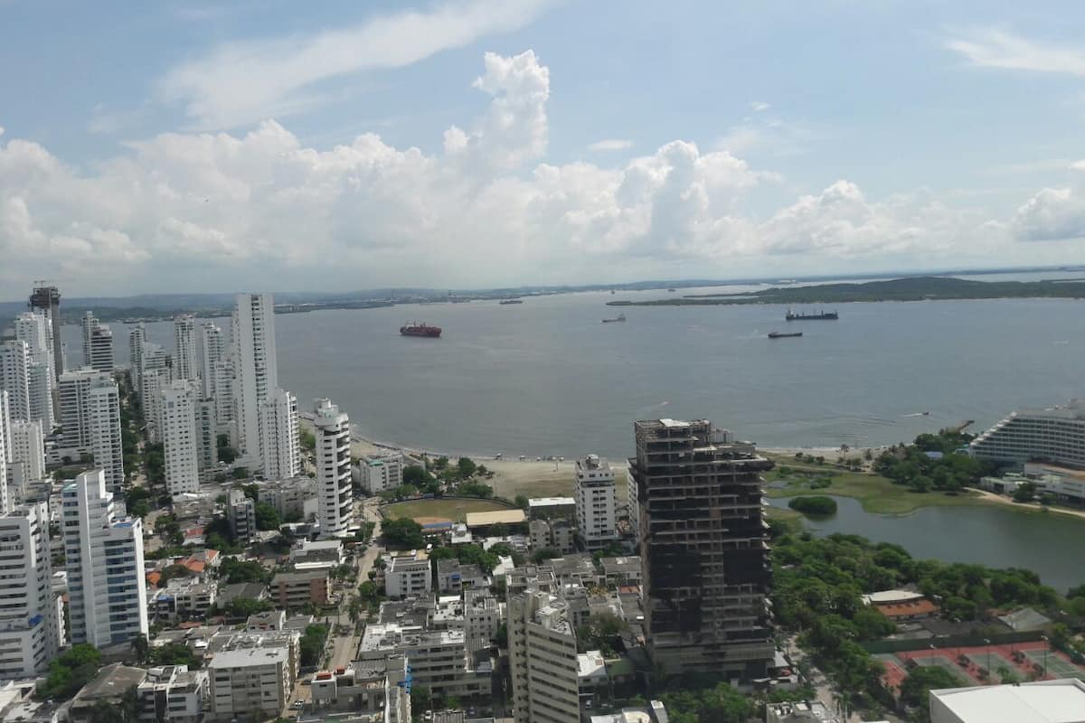 A coastal cityscape with high-rise buildings, a marina, and a large body of water.