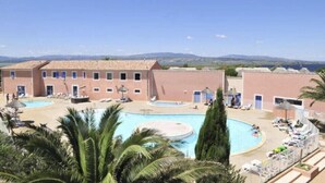 A hotel courtyard with a central pool, multiple lounge areas, and a view of distant mountains. - typical small house, air-conditioned fisherman's farmhouse (swimming pool, jacuzzi, sauna, fitness room) (Le Barcarès)